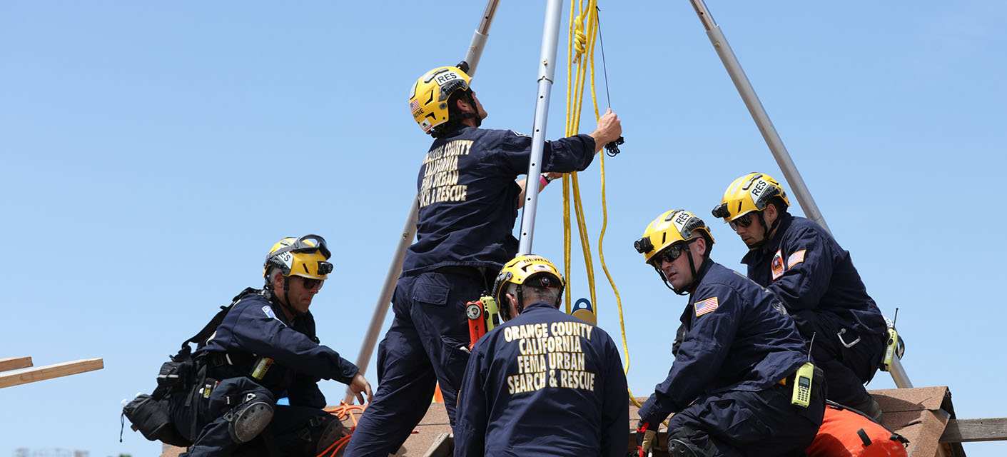 A group of five OC California FEMA Urban Search & Rescue workers preparing a hoist for a rescue operation