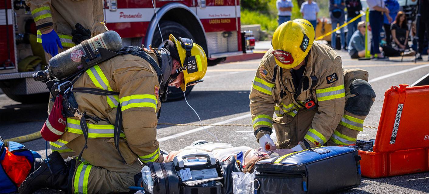 Two firefighters demonstrating a life-saving procedure on a mannequin